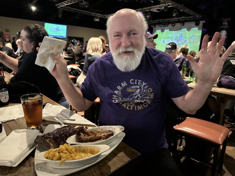 Ravens fan cheering with wings and fries at Twain's Tavern